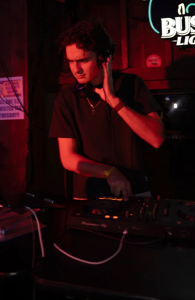 Lane Watt listening through headphones under red venue light