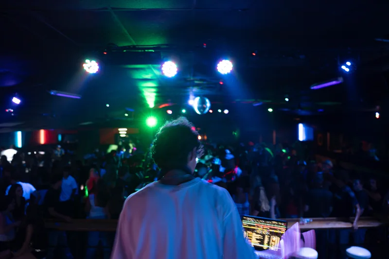 A wide view from the DJ booth facing a blue and teal-lit dance floor