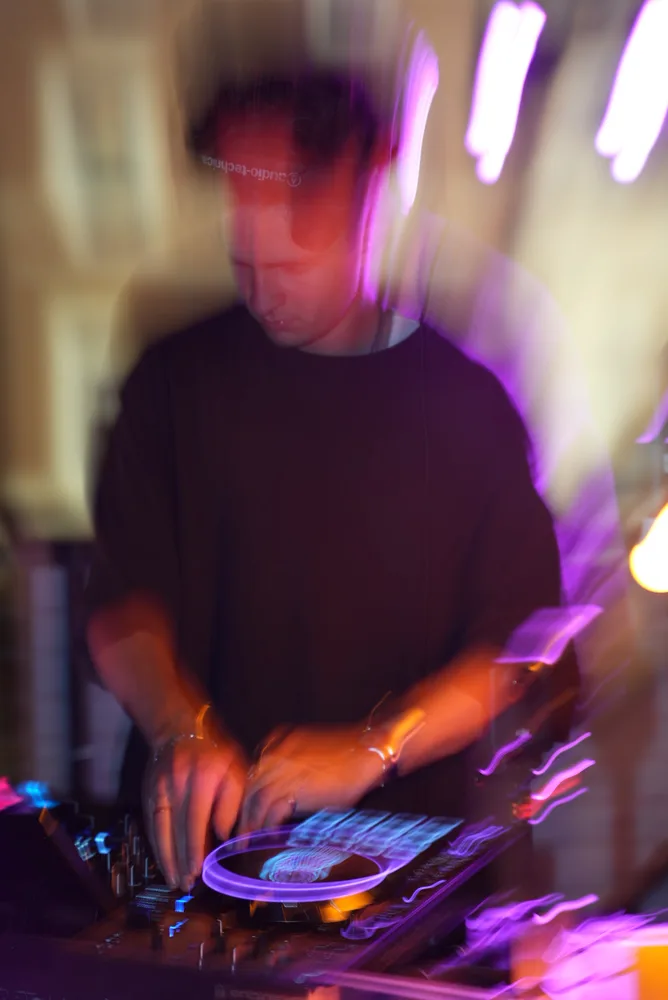 Motion-blurred performance photo with purple trails around the DJ booth