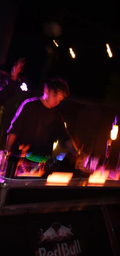 Lane Watt concentrating on the decks under purple room lights