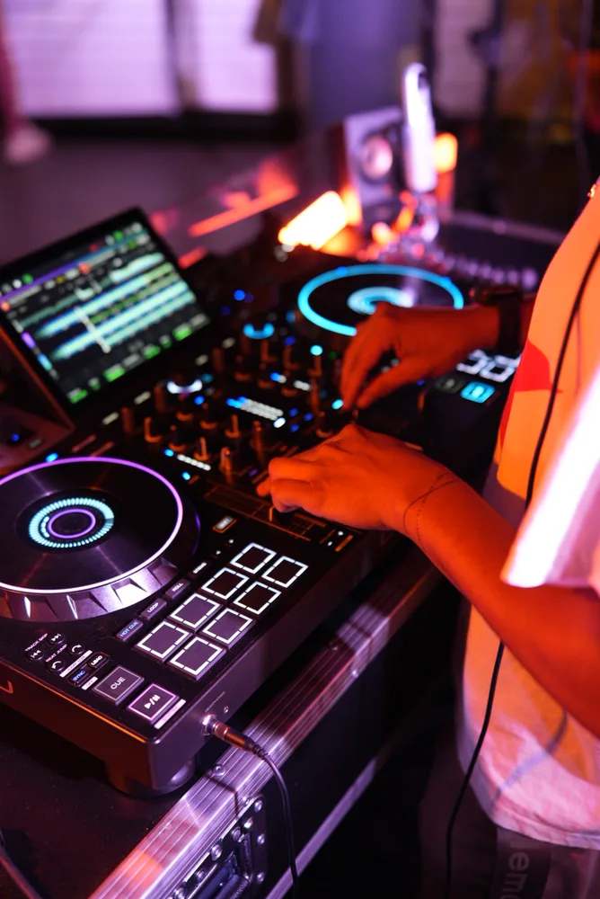 Close view of DJ controls and hands in orange and purple light